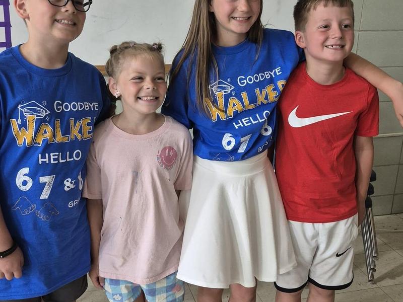 Four children posing for a photo in matching shirts, smiling happily.
