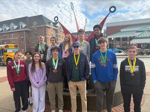 Image depicts a large group of students smiling with medals around their necks.