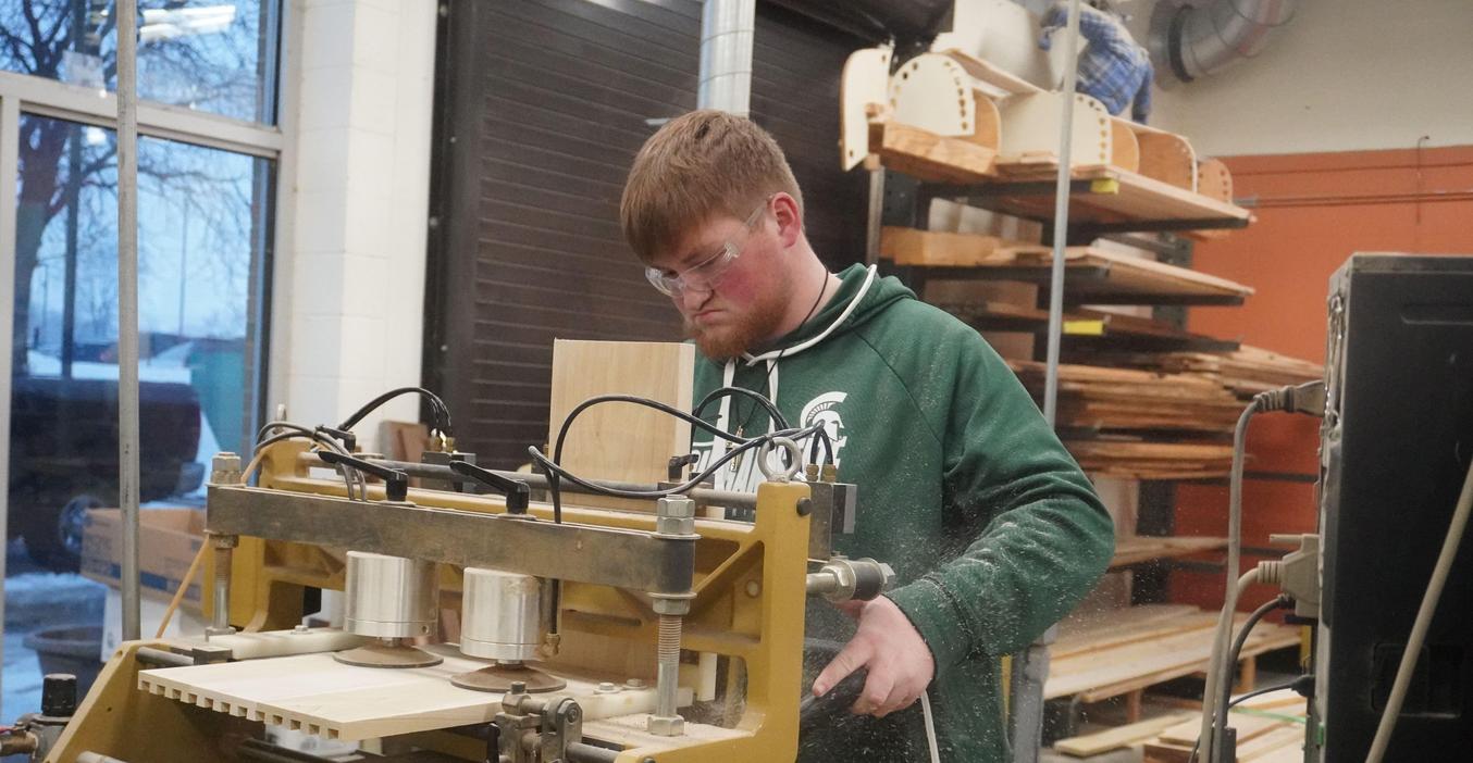 A student uses a machine in woodworking class.