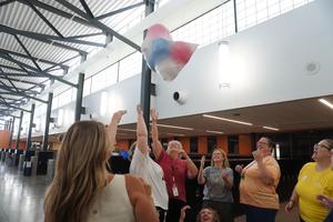 A group of employees work to keep a bag of balloons in the air.