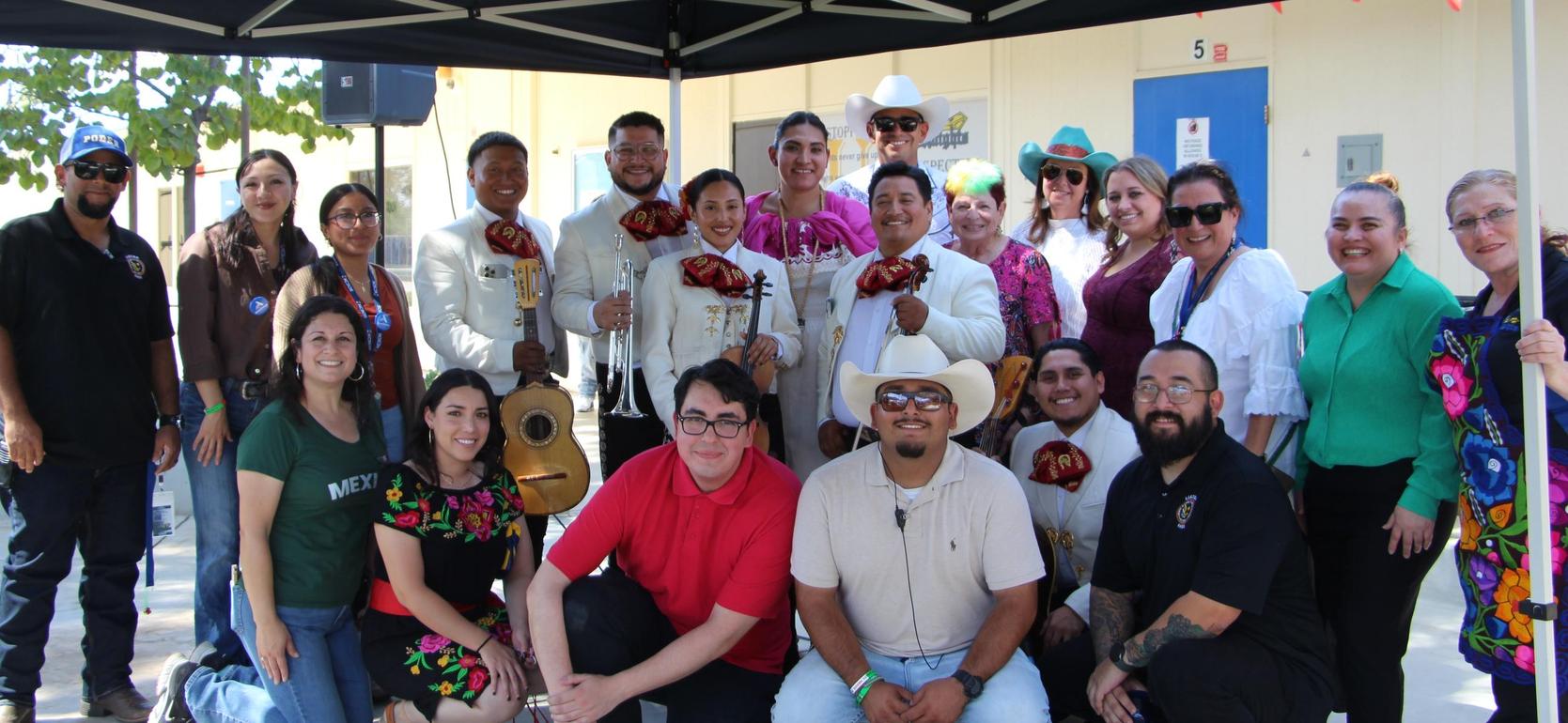 A group of people posing under a canopy at an outdoor event, smiling together.
