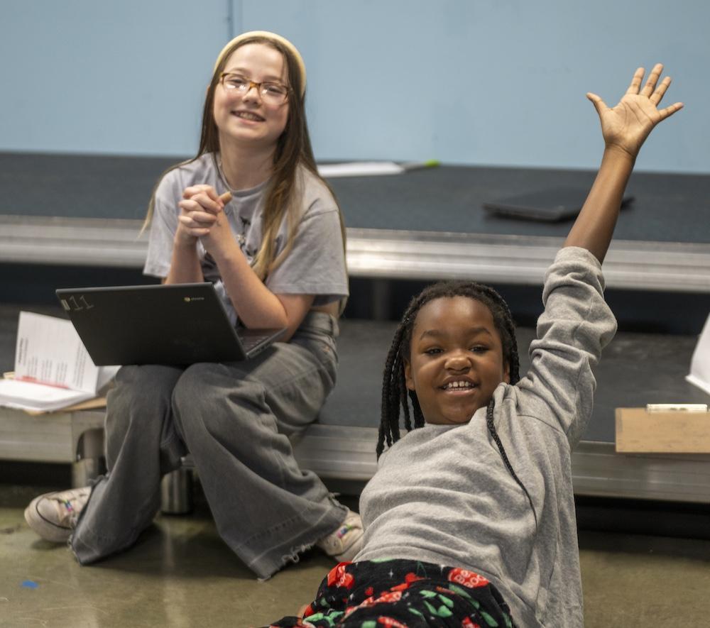 Two students and one is on floor having fun and raising hand for question