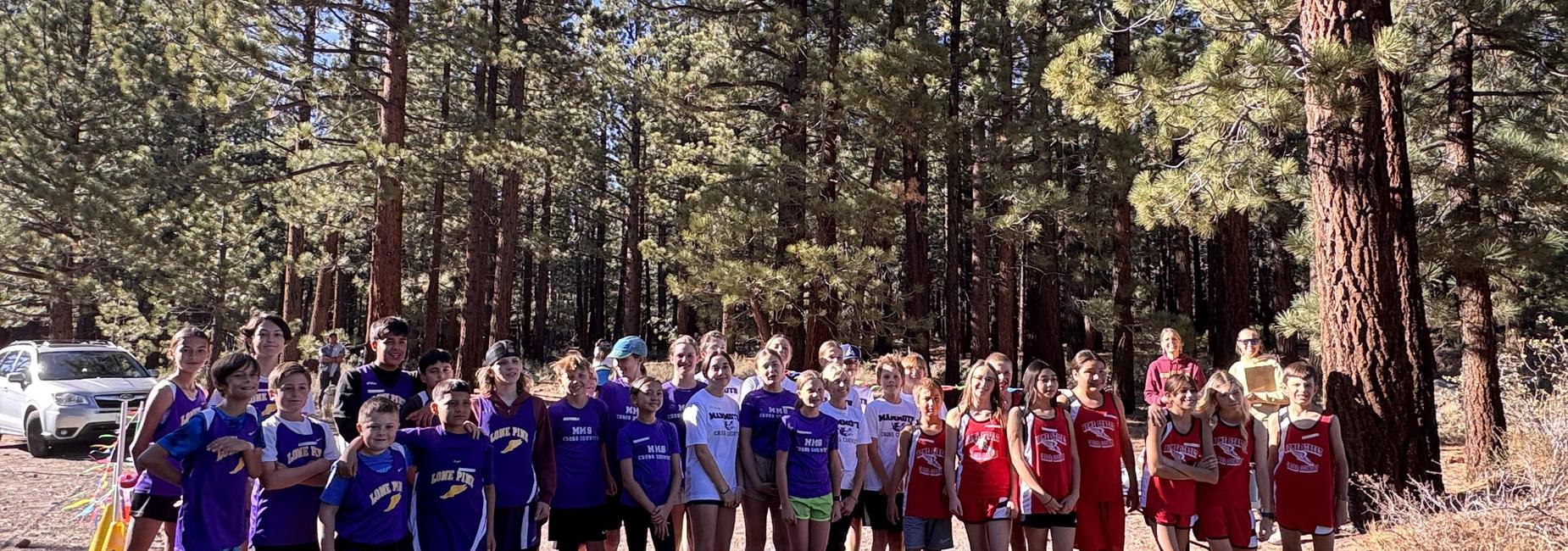 Athletes in purple and red jerseys posing together in a forested area.