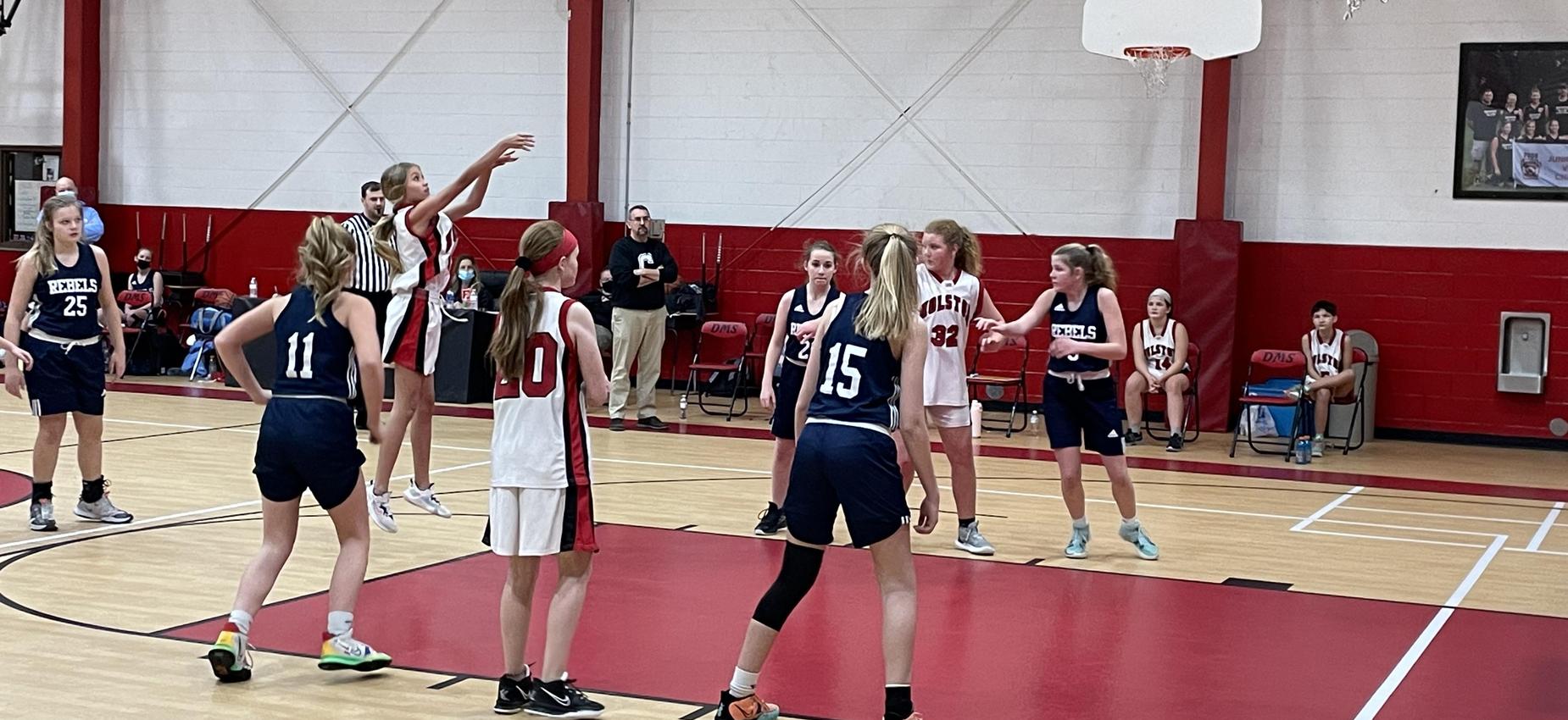 A basketball players shoots a foul shot in a gym.