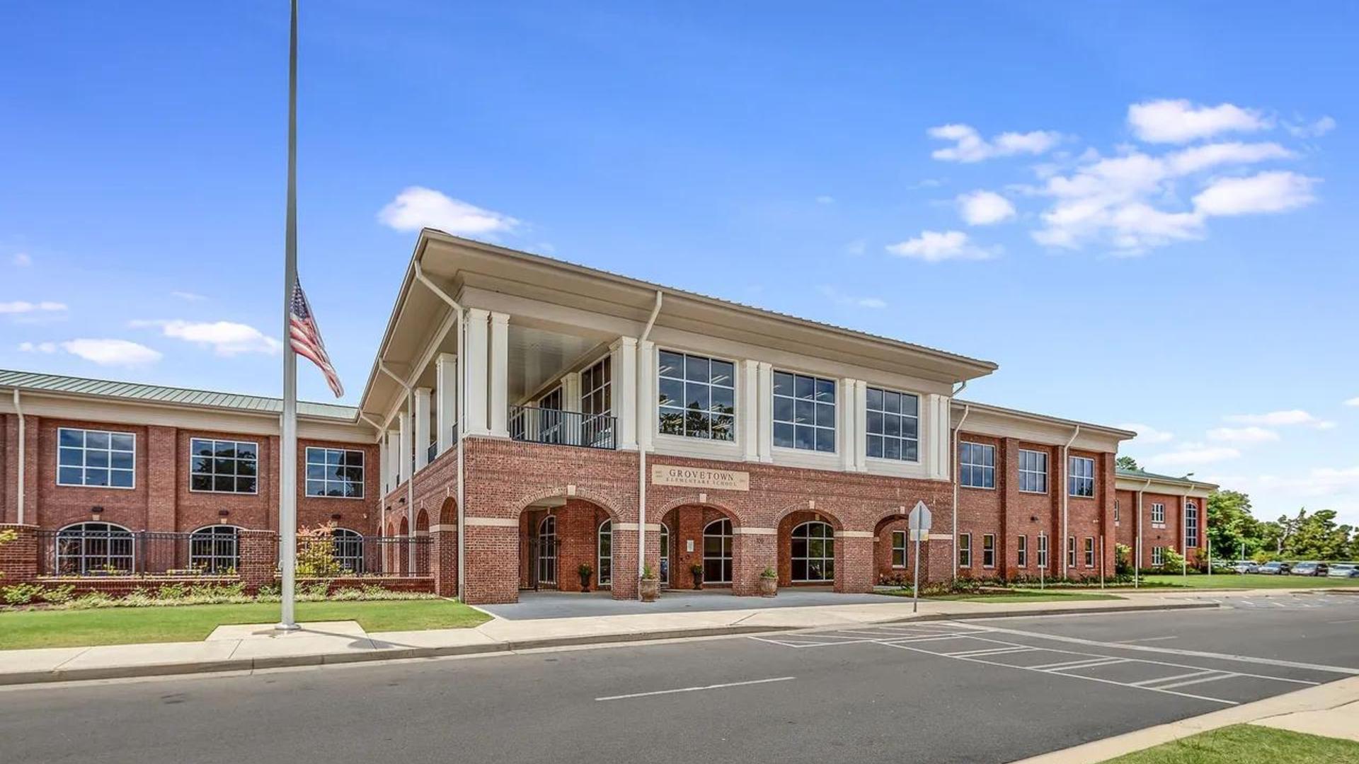 Large image of the Grovetown Elementary School building with large windows and American flag in a clear blue sky.