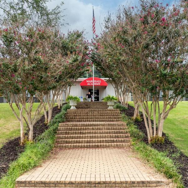 Entrance to Marshall Academy with steps and flowering trees.