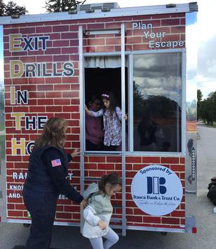 Children participating in a safety drill activity at a mobile training trailer.