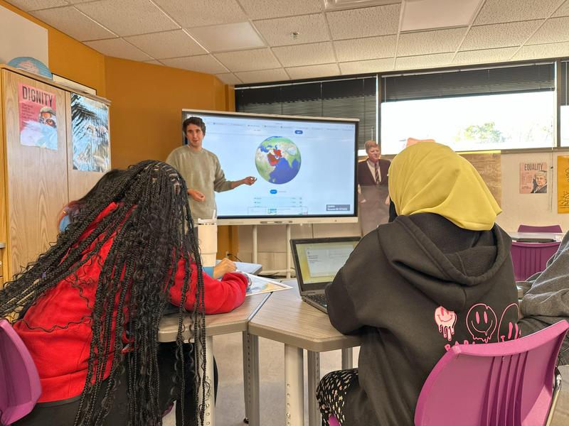 Two students paying attention to their teacher in class.