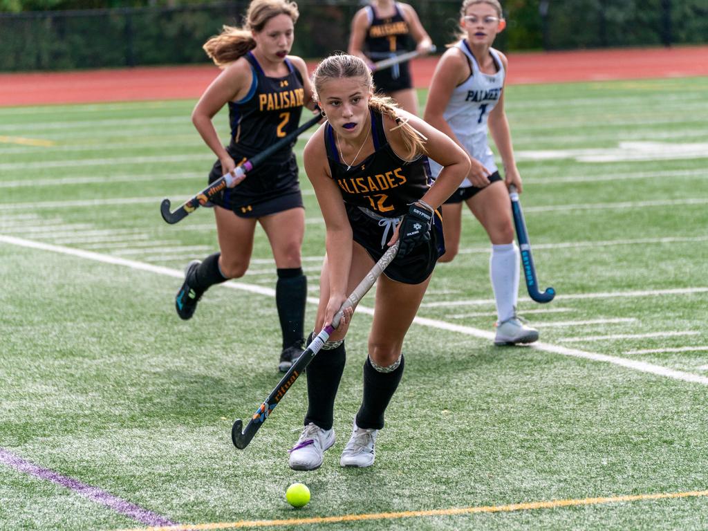 Field hockey players in a match on the field.