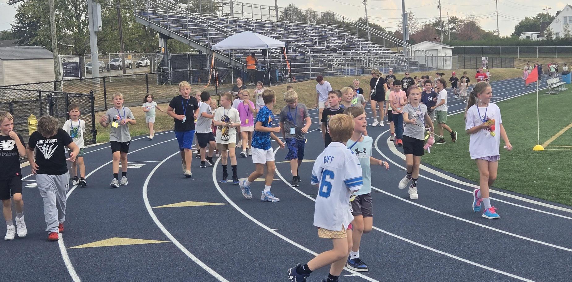 Students participating in a running event on a track with various activities happening.