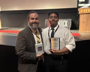 Ramses Gomez stands with Monache teacher Bobby Styles, both smiling and holding the award for Suicide Prevention PSA at the Slick Rock Student Film Festival.