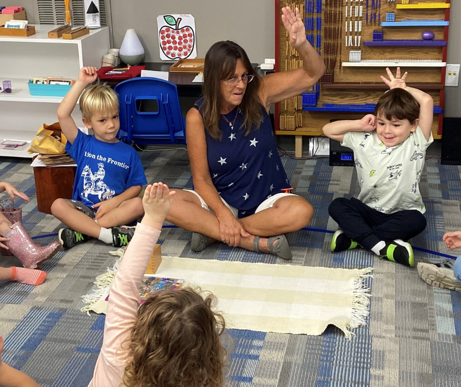 Teacher sits on floor with students