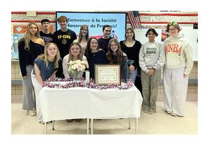 a group of students standing behind a table draped in a white cloth.