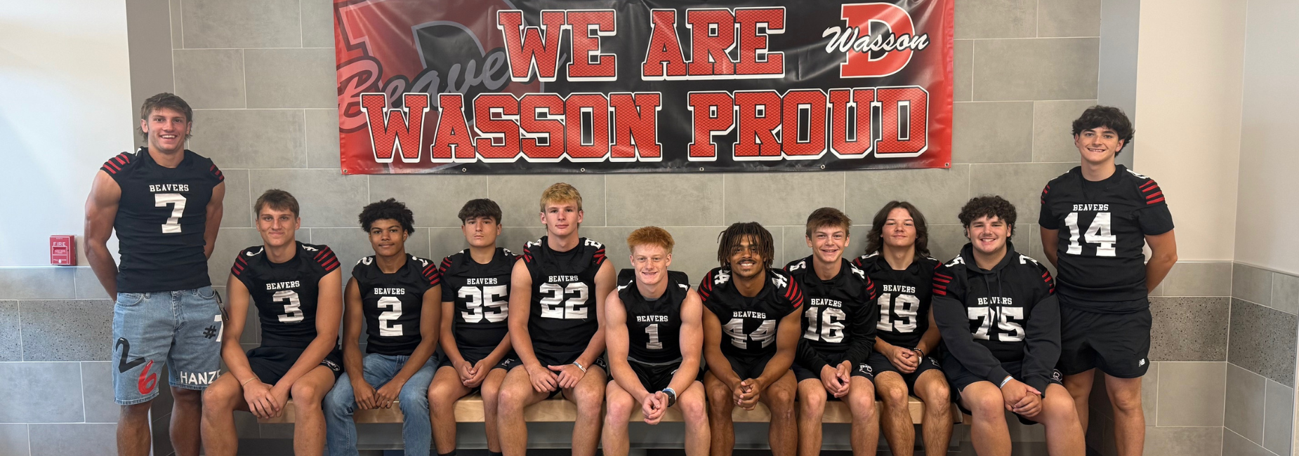 Team of football players in jerseys posing under a proud banner.