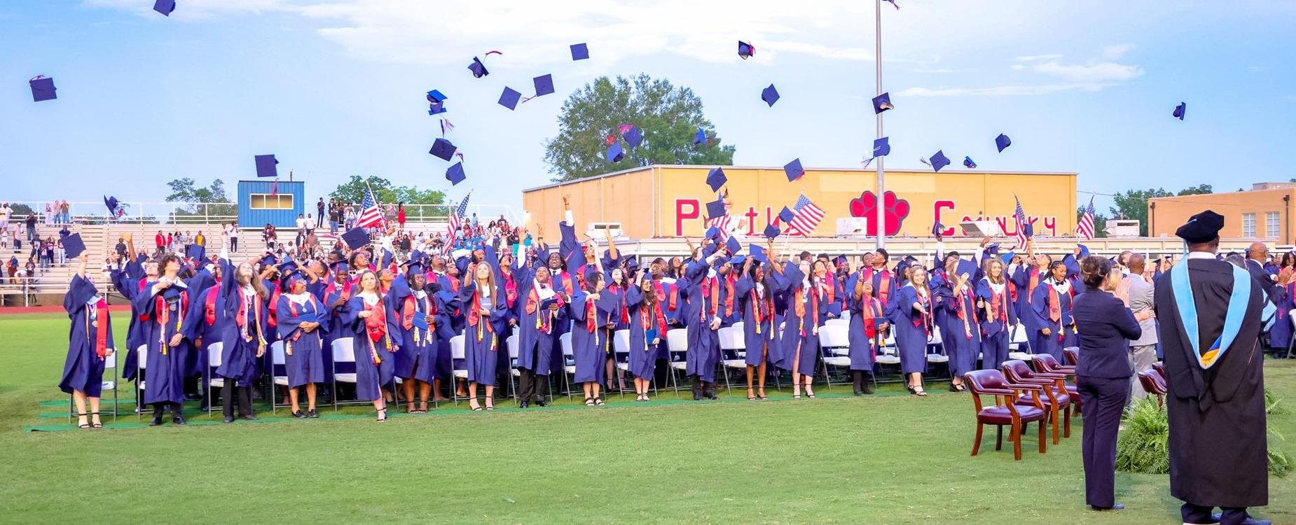 Graduates in caps and gowns celebrating at a graduation ceremony.