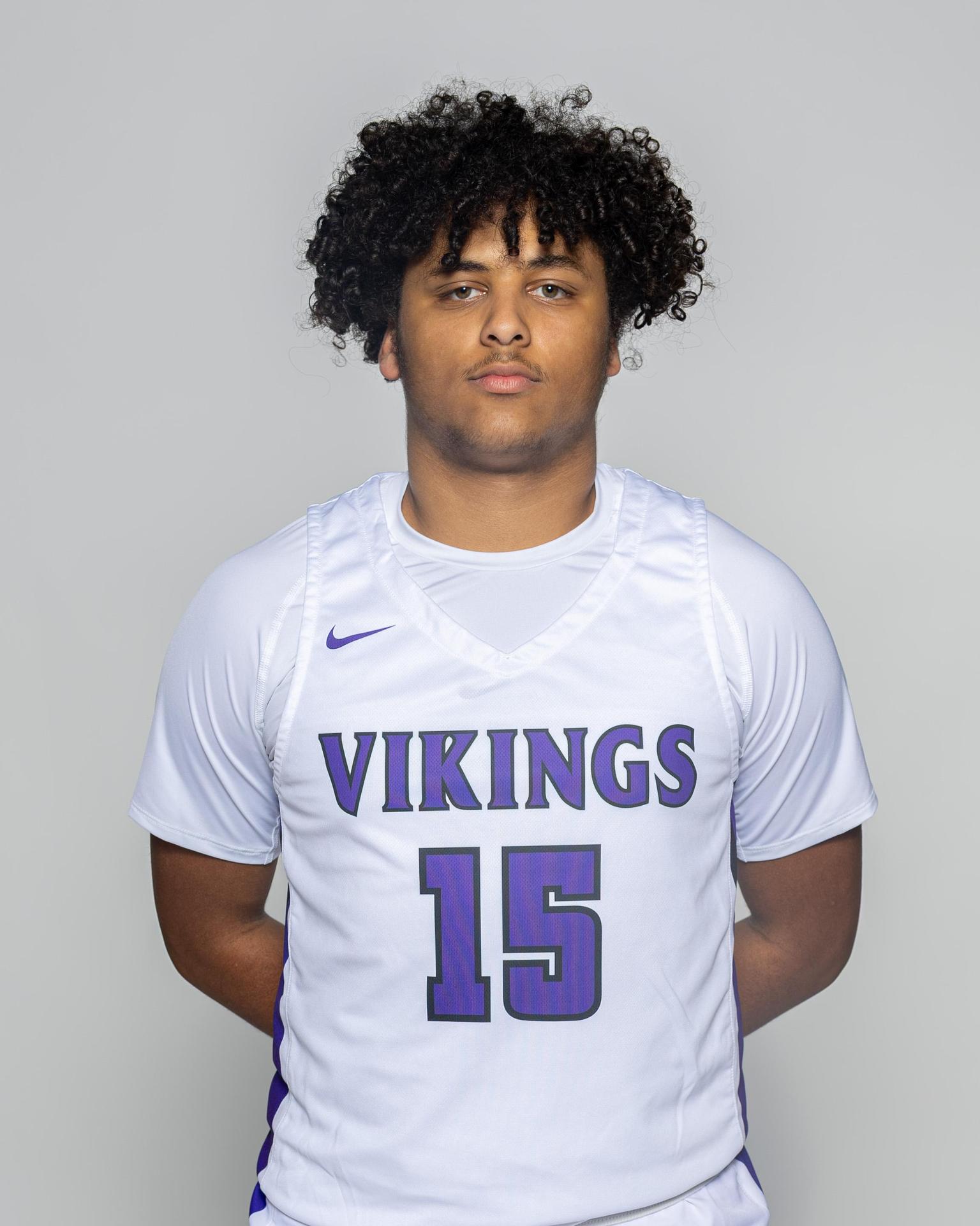 Teenage boy in a white basketball uniform with 'Vikings' and number 15.
