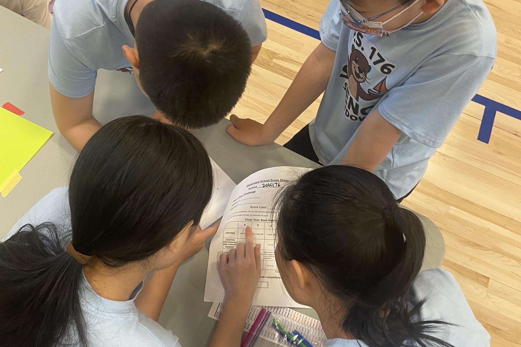 Four students closely examining a paper together.