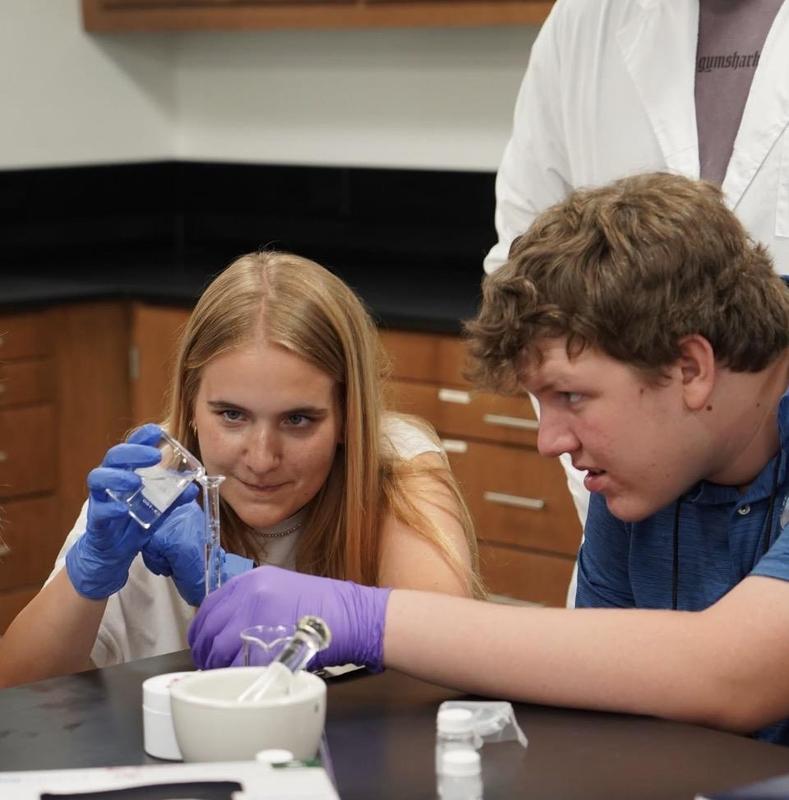 Ellie and another student working on a lab, pouring something into a tiny vial