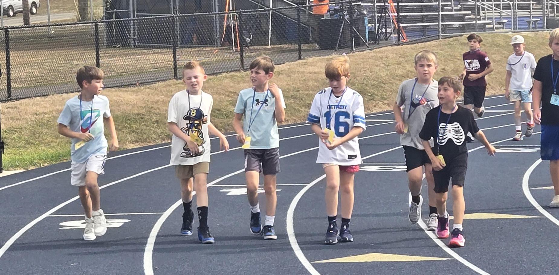 Group of boys walking together on a track during a school event outdoors.