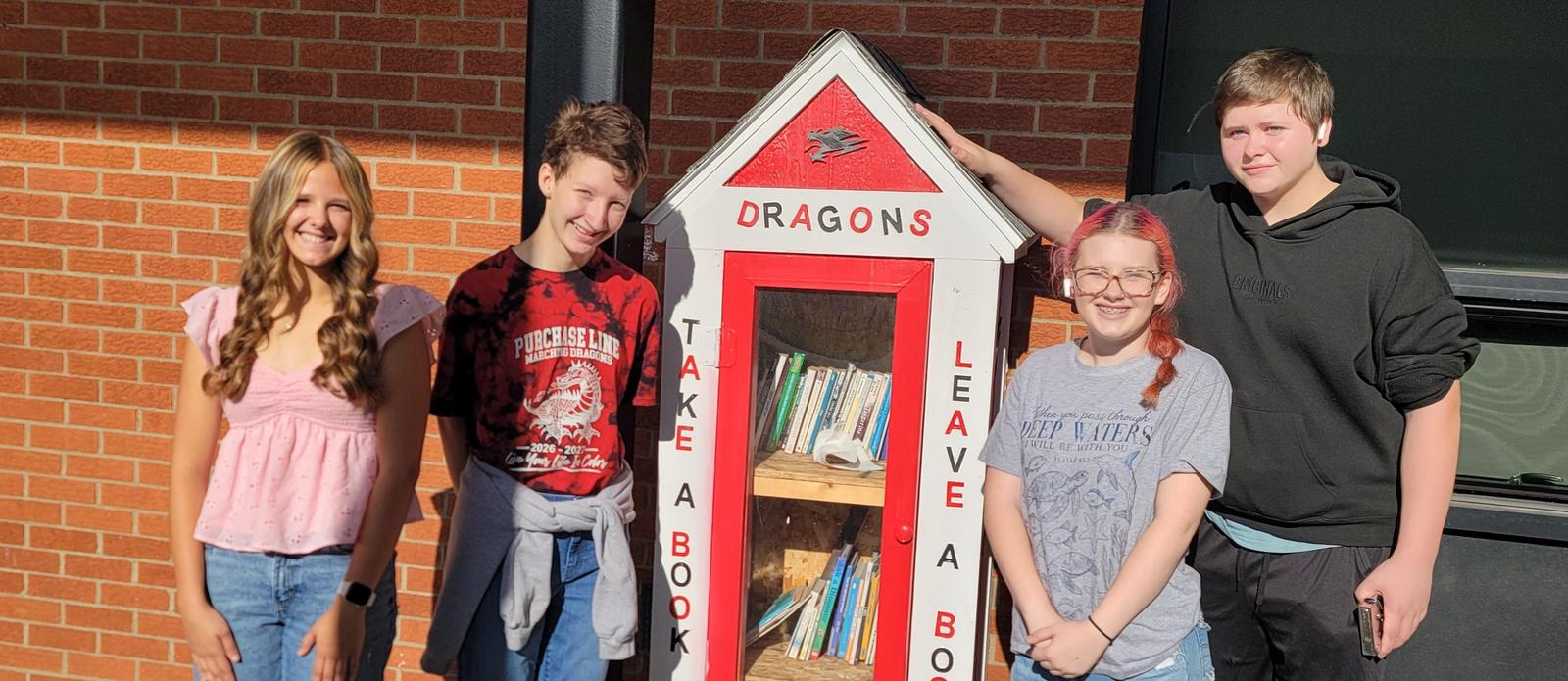 Students posed with the Take A Book/Leave A Book box located outside the elementray school. They refurbished it as part of the Day of Caring.