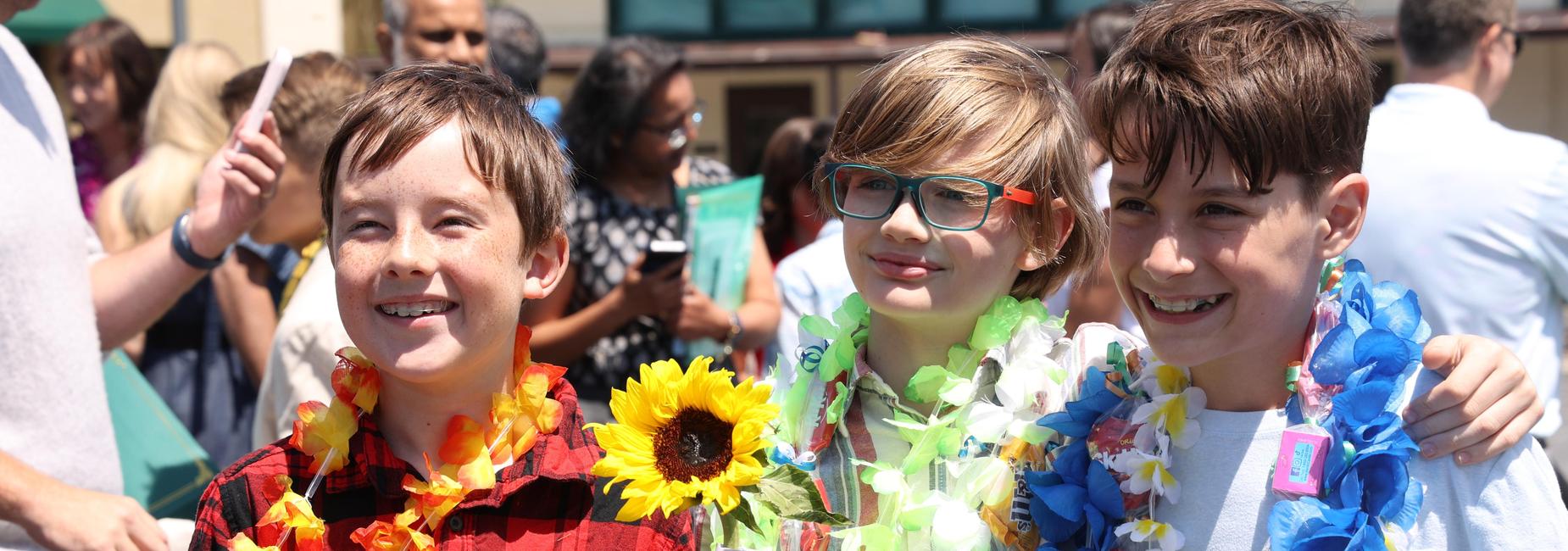 three boys smiling and wearing floral leis