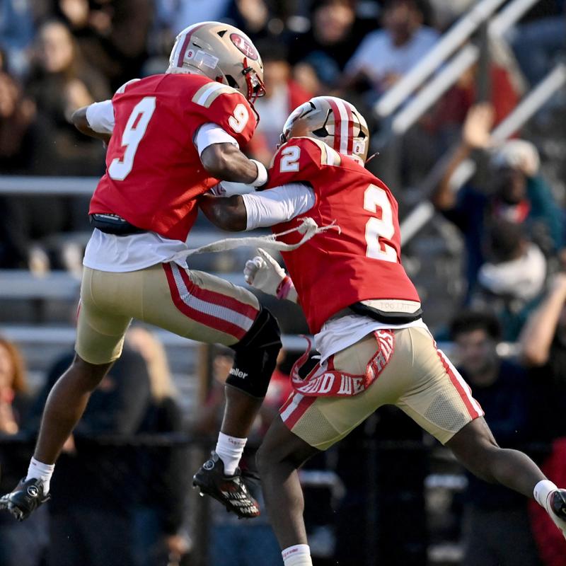 Two football players in red uniforms celebrating a touchdown on the field.