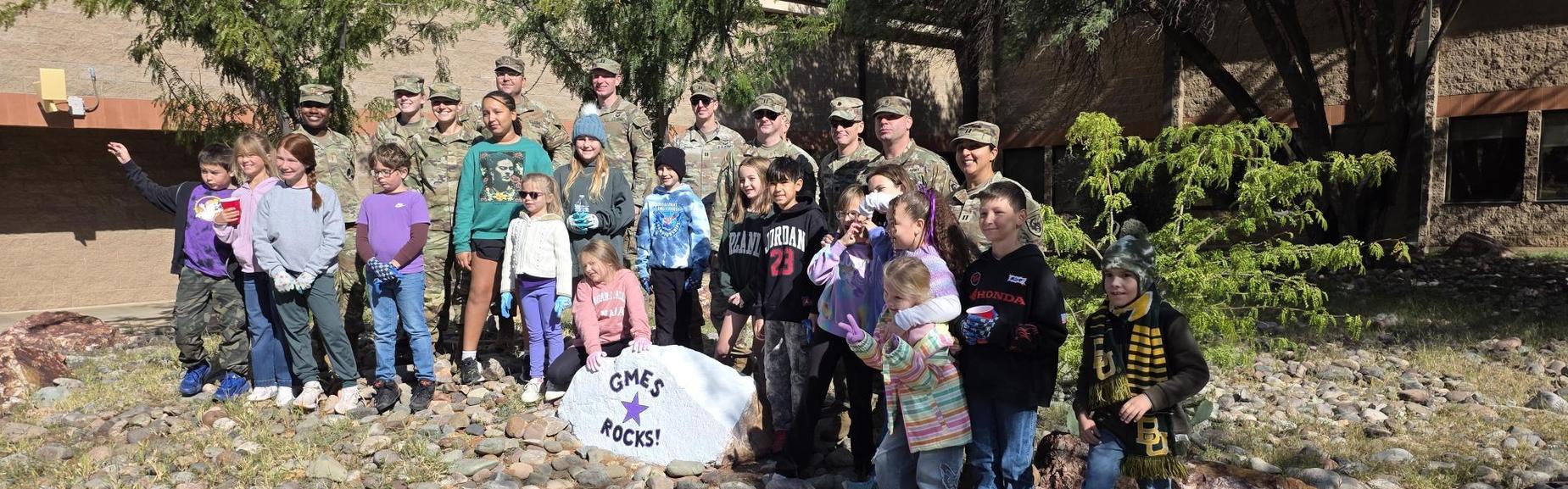 GMES student ambassadors pose with soldiers and painted rock titled, "GMES Rocks!"