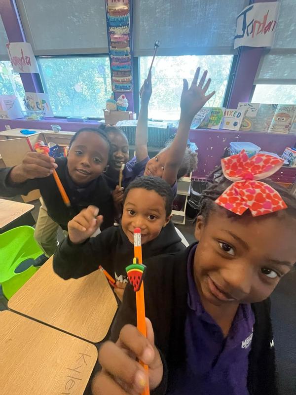 Scholars holding up pencils in the classroom