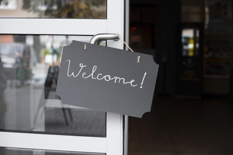 A sign with the word "welcome" hangs on an open door.