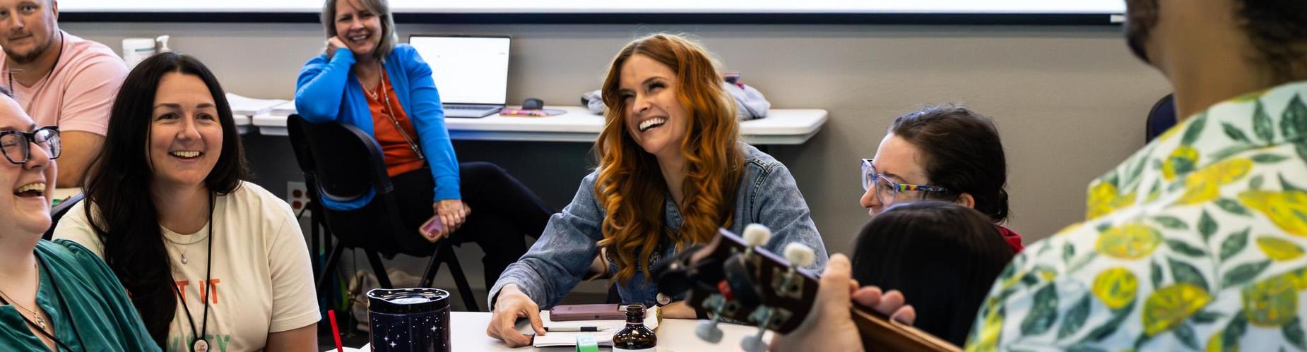 Group of people smiling and laughing in a casual meeting setting.