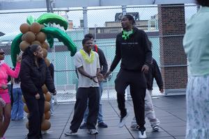 Teens interacting playfully around a balloon decoration while wearing colorful leis.