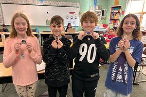 Isabelle Govert, Boden Ruzich, Caden Hoyman, and Aria Matthews hold some of the science stickers