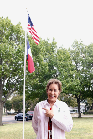 superintendent pointing with american and texas flags behind her