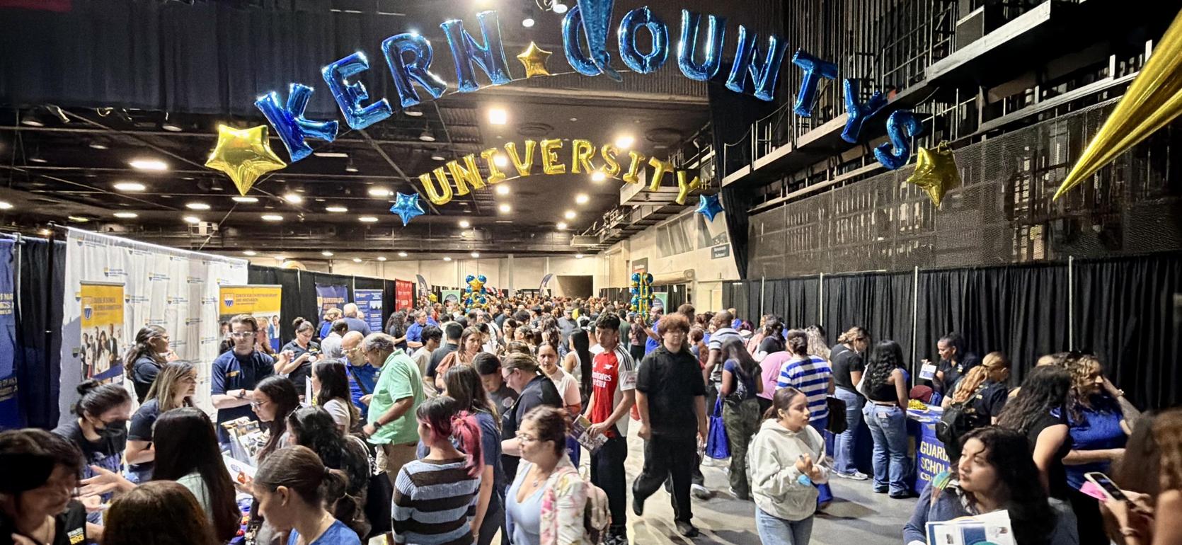 Crowd at Kern County University event with booths and banners.