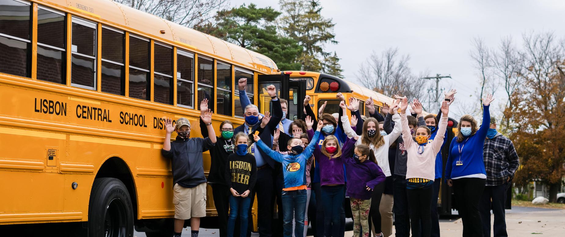 students and staff in front of the new school buses
