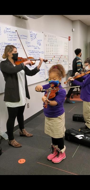 Image shows violin teacher and scholar performing together in a classroom