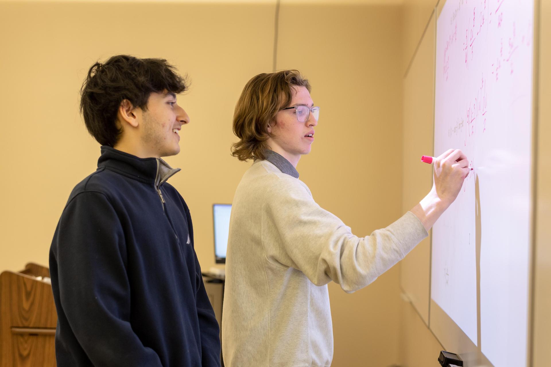 Upper school students solving an equation at the board