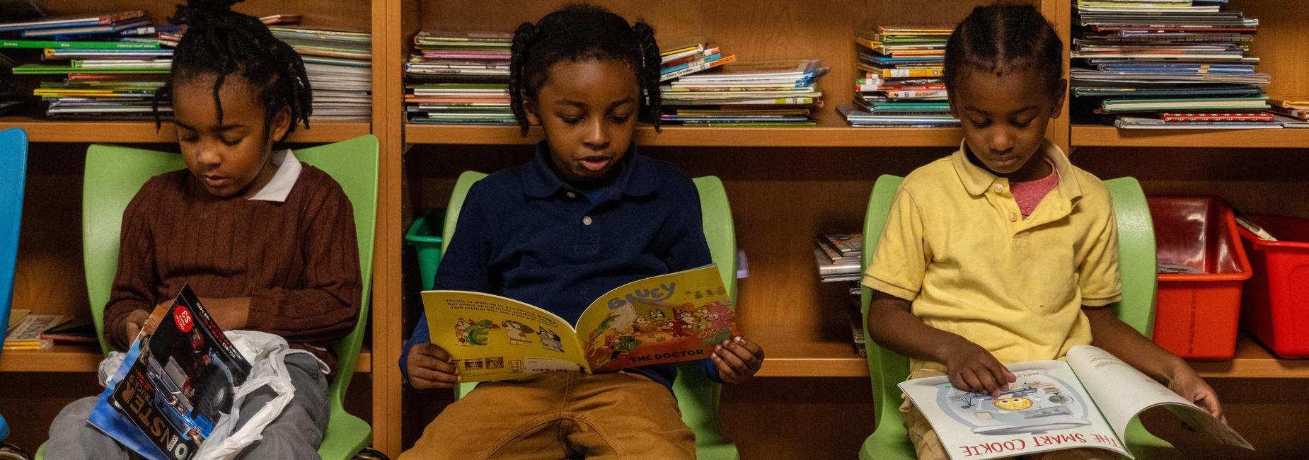 Three students sit and read in a library