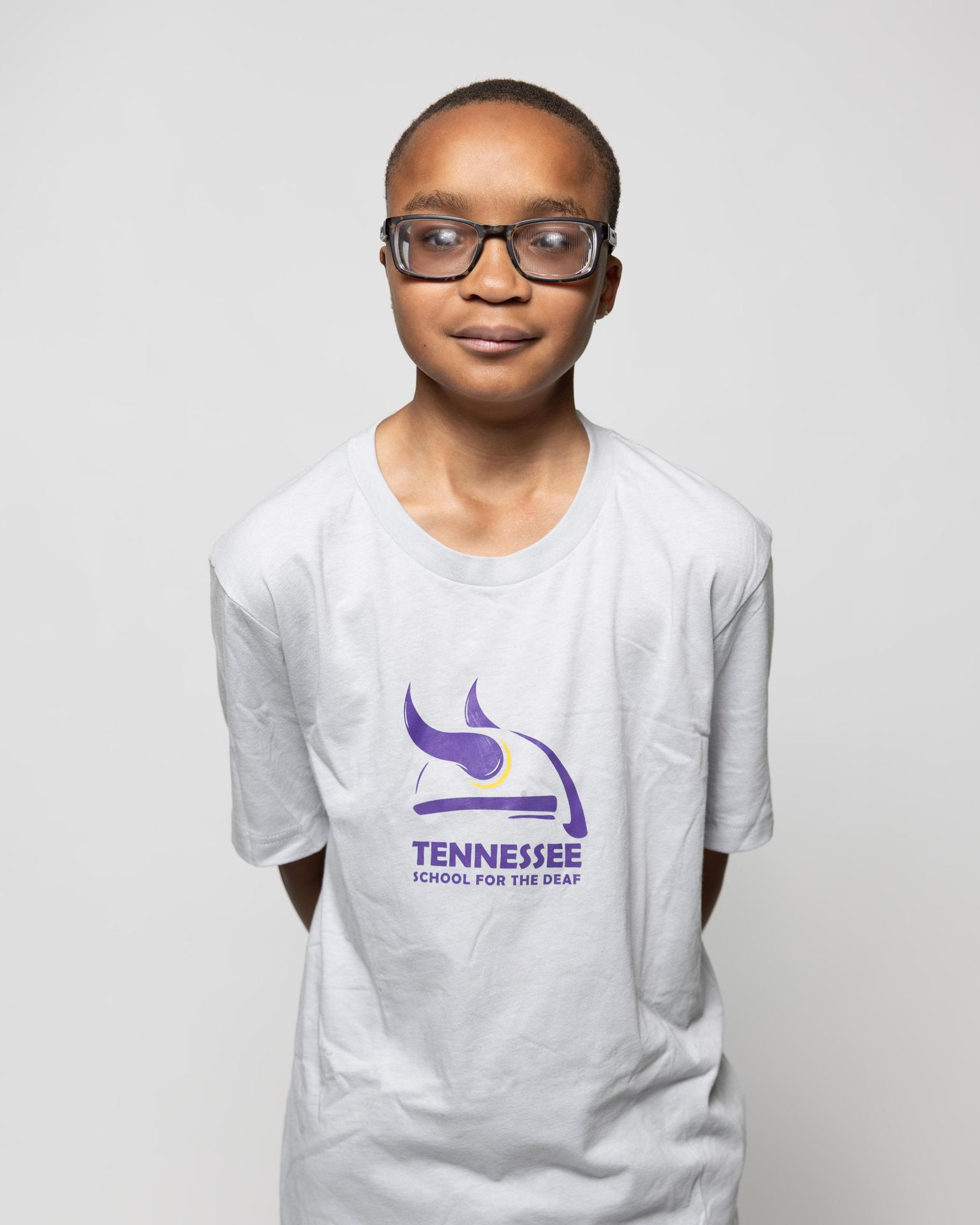 Boy wearing a white t-shirt with a logo for Tennessee School for the Deaf.