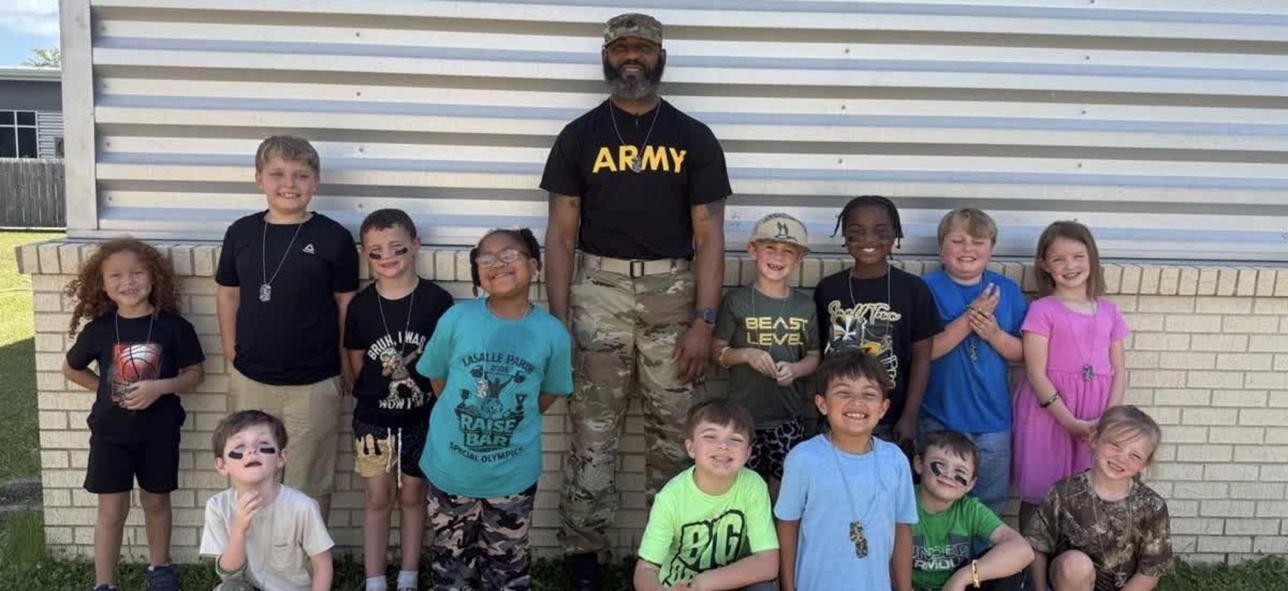 Children with face paint posing in front of a soldier in military gear.
