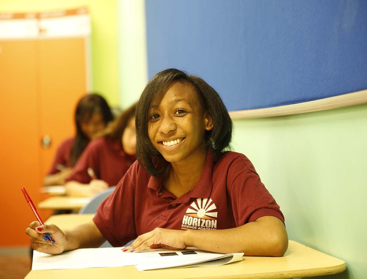 Elementary student smiling and posing together in a classroom.
