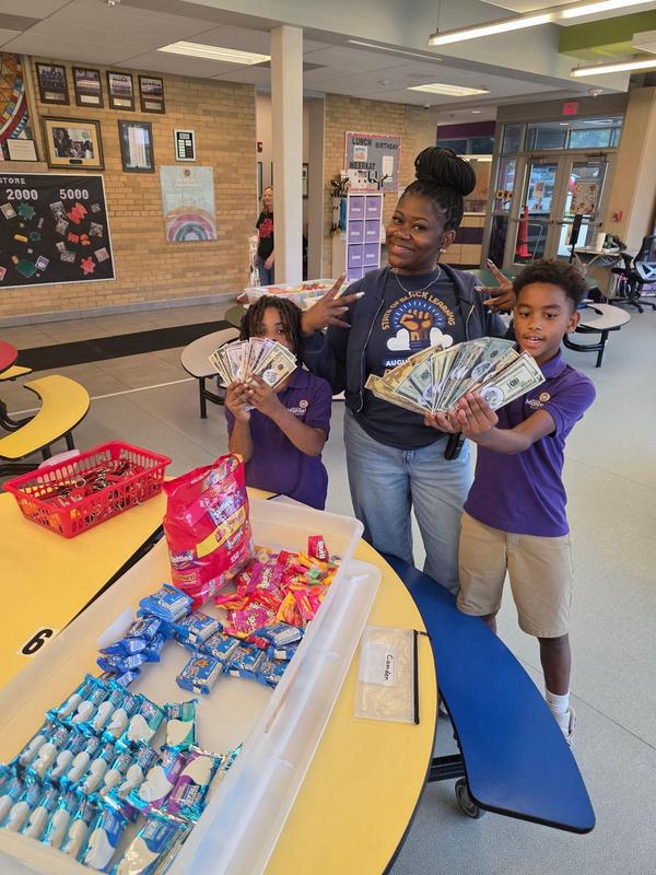 Scholars holding up their fake money for the school store