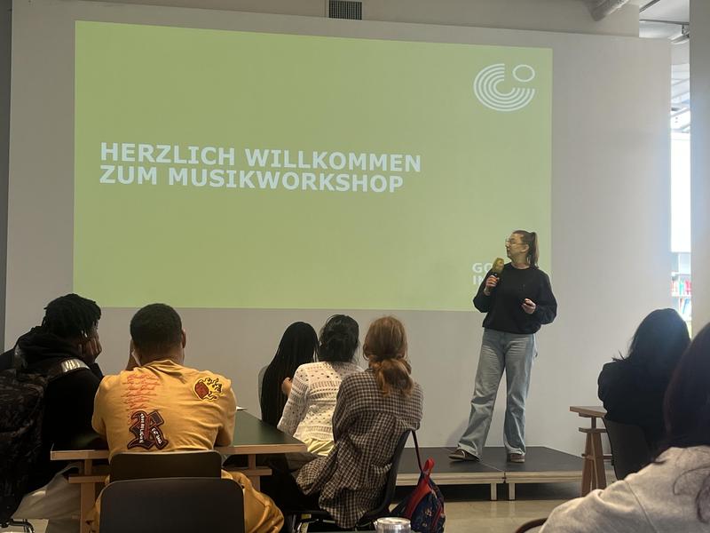 Workshop welcome slide with a presenter addressing an audience.