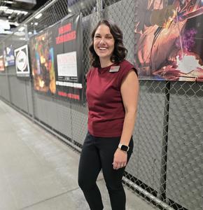 woman standing in front of fence with cte poster in a red shirt and black pants