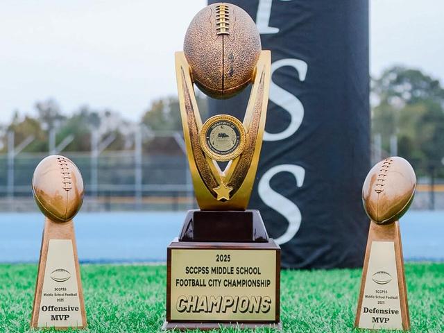 2025 Championship trophy with football and two MVP trophies beside it.