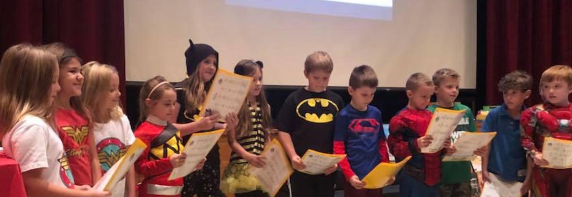 Students presenting on super heroes at an assembly