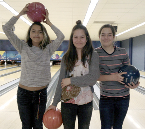 Three girls posing with bowling balls