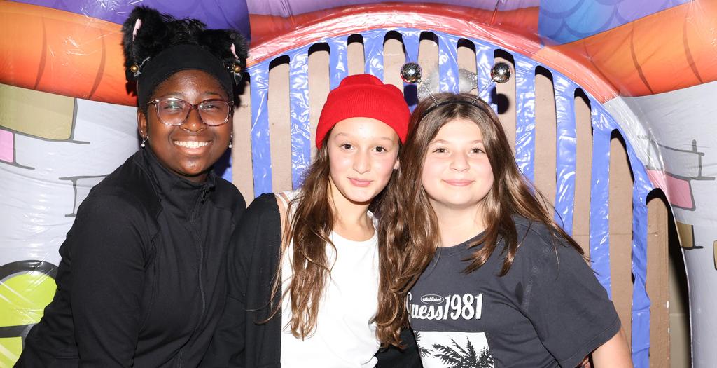 Three girls dressed in Halloween costumes in front of Halloween display.