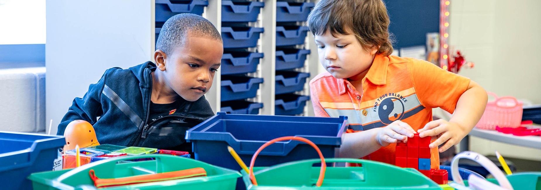 Two boys collaborating on building projects with toys.
