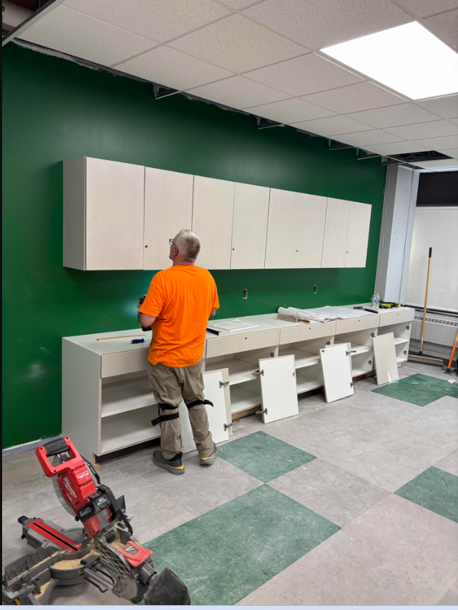 Worker puts cabinets into classroom space
